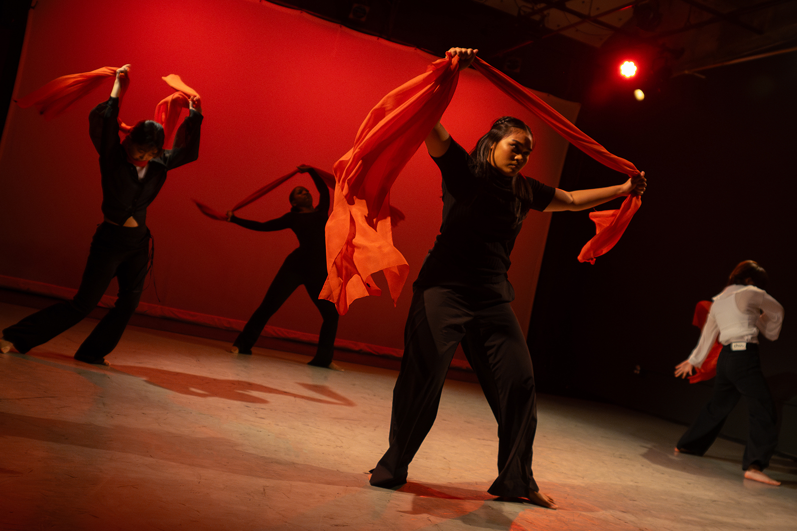"Let There Be Light" by Lilea Alvarez Four dancers perform with red scarves against a red backdrop