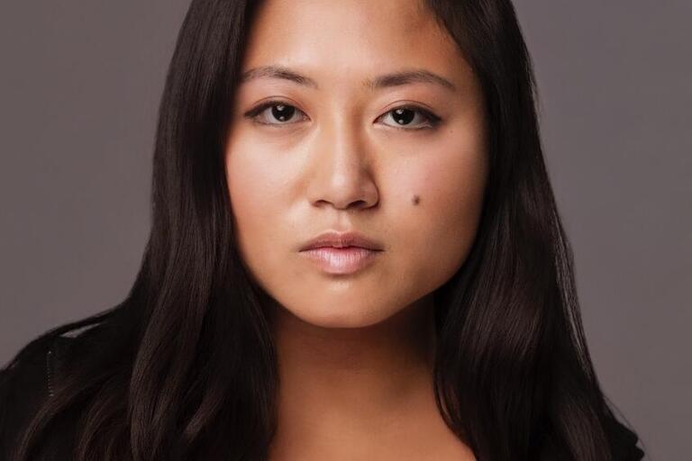 A headshot of Belle Ramos who is wearing a black top and looking directly into the camera.