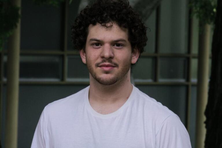 A headshot of Joshua Delman, he is wearing a white shirt and looking straight into the camera.