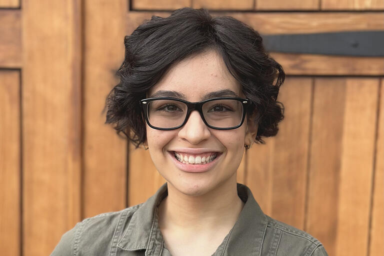 A portrait of Isabelle Morales. They have short, dark hair and black glasses.