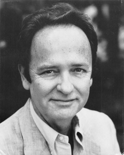 A black and white portrait of Robert Goldsby. He has short, dark hair and is wearing a button down shirt and suit jacket.